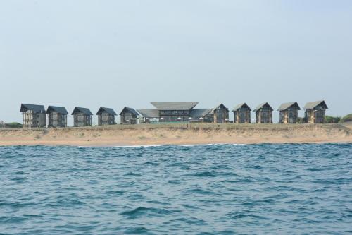 a row of houses on the beach next to the water at Laya Safari Resorts & Spa in Yala