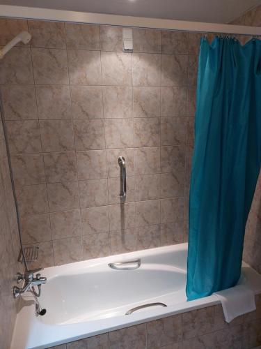 a bath tub with a shower with a blue shower curtain at Albufeira Paradise in Albufeira