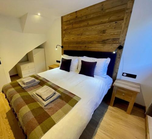 a bedroom with a large bed with a wooden headboard at La Chaumine - Beautiful & Stylish 2 Floor Apartment With Terrace in Montriond