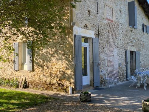 un edificio de piedra con una puerta blanca y una mesa en Maison d'Emmannaelle en Auros