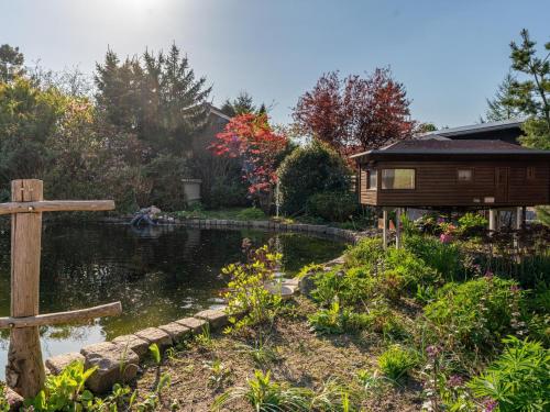 a garden with a pond and a wooden house at Vakantiehuis Das in Hulshorst