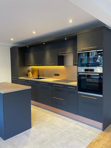 a large kitchen with black cabinets and a stove at La Chaumine - Beautiful & Stylish 2 Floor Apartment With Terrace in Montriond