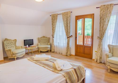 a bedroom with a bed and two chairs and a television at Popasul Craiului in Zărneşti