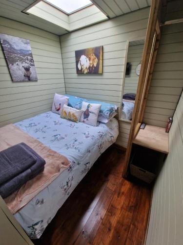 Stunning 1-Bed shepherd hut in Holyhead في هوليهيد: غرفة صغيرة مع سرير في منزل