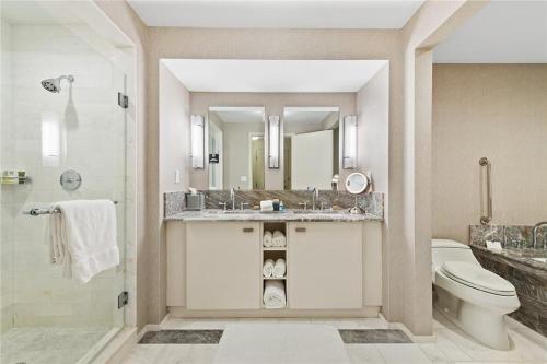 a bathroom with a sink and a toilet and a mirror at High Floor Unit at Luxury Hotel/Ocean & City views in Fort Lauderdale