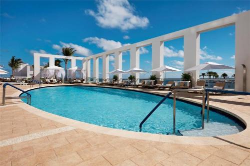 a swimming pool with chairs and umbrellas on a building at High Floor Unit at Luxury Hotel/Ocean & City views in Fort Lauderdale