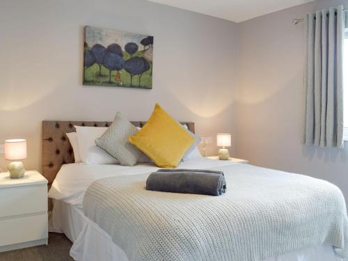 1 dormitorio con cama blanca y almohada amarilla en Oak Cottage - Uk11212, en Walton West