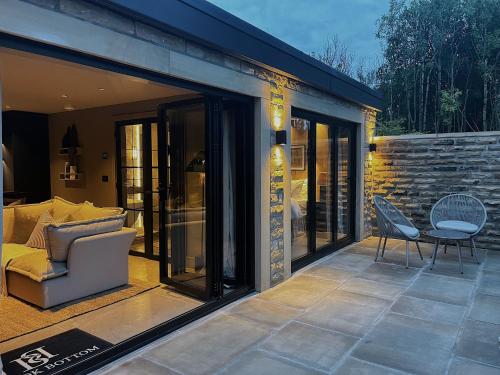 patio con puertas correderas de cristal, sofá y mesa en Apartments for two in Brand New Luxury Rural Farmhouse Escape, en Ramsbottom