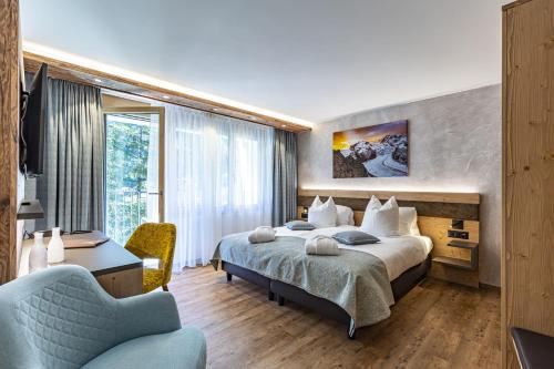 a hotel room with a bed and a chair at Hotel Hemizeus & Iremia Spa in Zermatt
