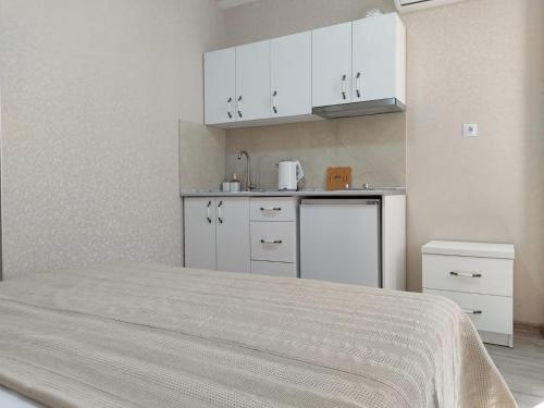 a kitchen with white cabinets and a bed in a room at Pushkin street Pearl in Kutaisi