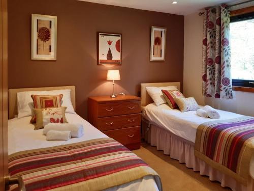a bedroom with two beds and a dresser at Assynt Chalet - Uk30806 in Lochinver