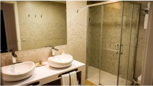 a bathroom with two sinks and a glass shower at Apartamentos Rondacentro in Ronda