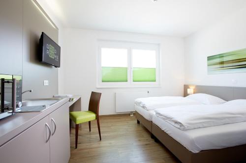 a hotel room with two beds and a sink at Good Rooms GmbH Guntramsdorf in Guntramsdorf