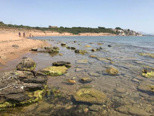 a beach with rocks and people walking on the beach at Hotel Miramare Garzia in Marinella di Selinunte