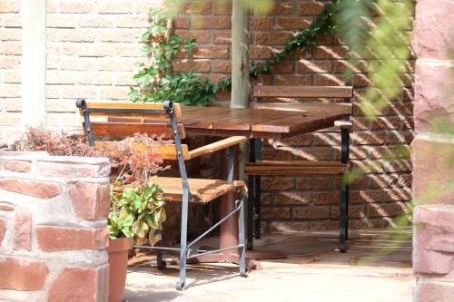 a wooden table and two chairs next to a brick wall at Duwisib Guest Farm in Duwisib