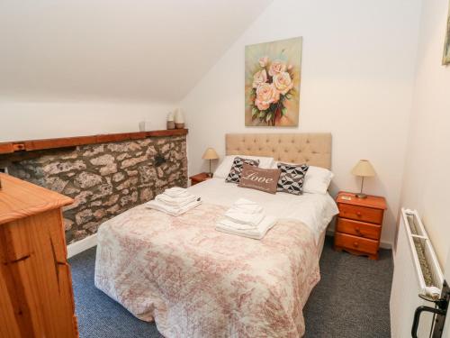 a bedroom with a bed and a stone wall at Beekeeper's Cottage in Lamphey
