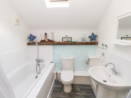 La salle de bains est pourvue de toilettes, d'une baignoire et d'un lavabo. dans l'établissement Beekeeper's Cottage, à Lamphey