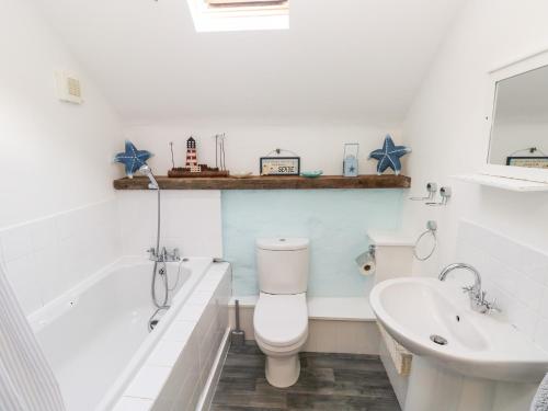 a bathroom with a toilet and a tub and a sink at Beekeeper's Cottage in Lamphey