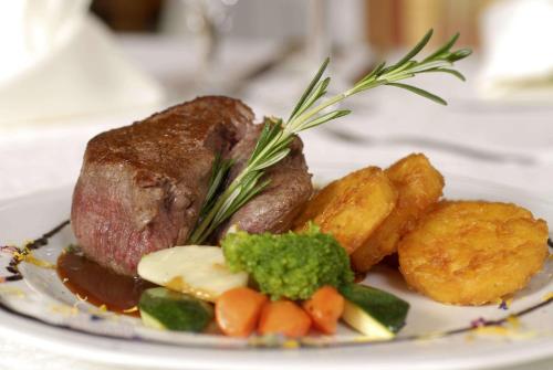 a plate of food with a piece of meat and vegetables at Alpensporthotel Mutterberg in Mutterbergalm