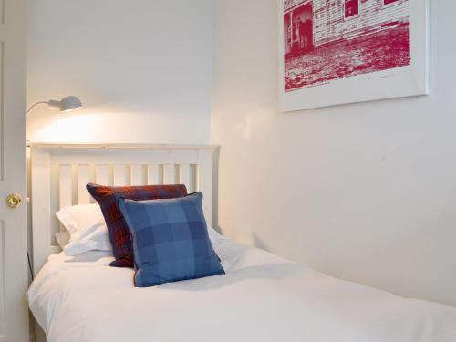 a white bed with a blue pillow on it at Secret View Cottage in Terrington