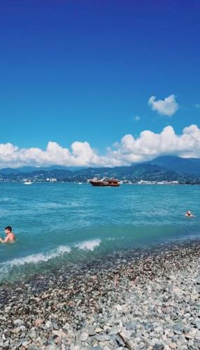 a person swimming in the water on a rocky beach at Old BATUMI MGZAVREBI APARTMENTS in Batumi