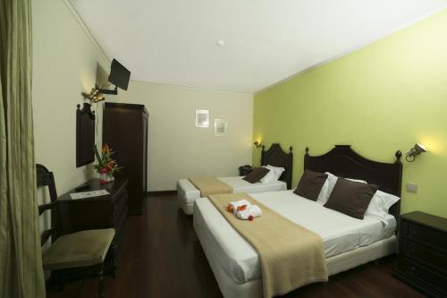 una camera d'albergo con due letti e una sedia di Hotel Sirius a Funchal