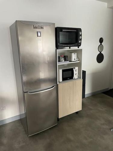 une cuisine avec un réfrigérateur en acier inoxydable et un micro-ondes dans l'établissement Bel appart spacieux 10min centre 300m quai de Seine WIFI, à Rouen