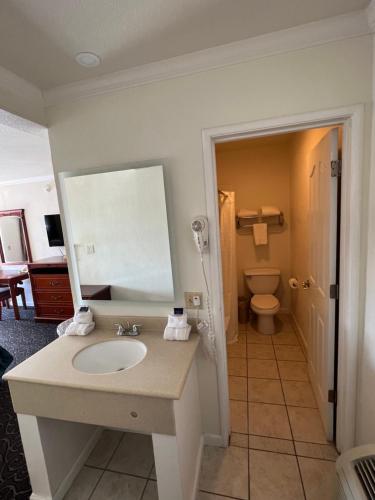 y baño con lavabo, espejo y aseo. en Americas Best Value Inn Hanford en Hanford