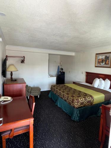 ハンフォードにあるAmericas Best Value Inn Hanfordのベッドとテーブルが備わるホテルルームです。