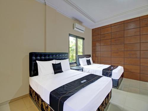 a hotel room with two beds and a window at Collection O 91666 Meyli Guesthouse in Cilacap