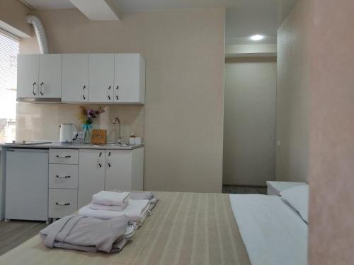 a kitchen with white cabinets and towels on a bed at Pushkin street Pearl in Kutaisi