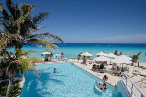 une piscine avec l'océan en arrière-plan dans l'établissement Frente al mar, increíble vista, nuevo estudio 1 C, à Cancún