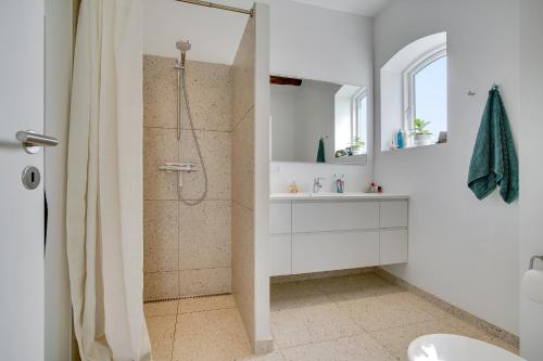 baño blanco con ducha y lavamanos en Pakhuset en Løkken