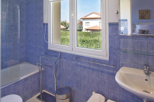 baño de azulejos azules con lavabo y ventana en CASONA QUINTA HERMINIA, en Gijón