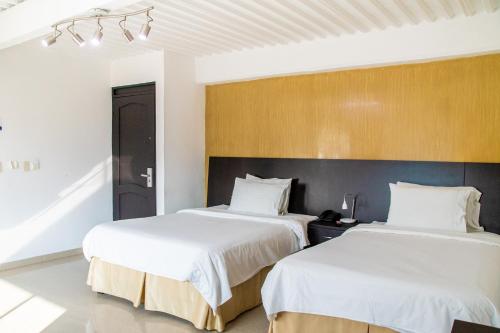 two beds in a hotel room with white sheets at HOTEl TANGARA in Pereira