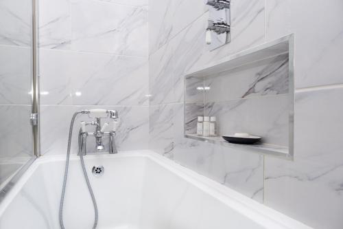 a white bathroom with a tub and a shower at Arthur Turner, The Apple Rooms in Stockbridge