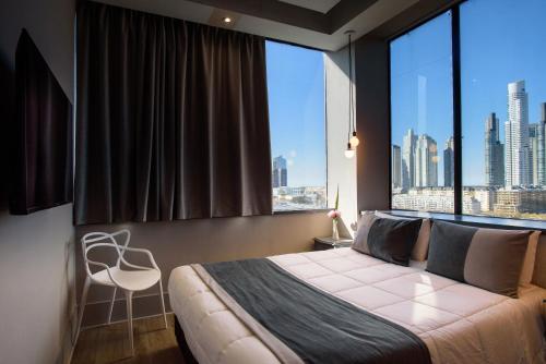 una camera da letto con una grande finestra con un letto e una sedia di Believe Madero Hotel a Buenos Aires