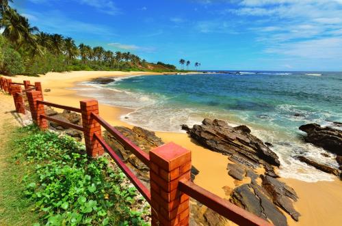 a beach with a wooden fence and the ocean at Eva Lanka Hotel - Beach & Wellness in Tangalle