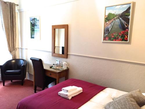 a hotel room with a bed and a desk with a mirror at Fairlawns Guest House in Banbury