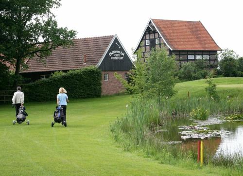 two people walking in the grass with their luggage near a pond at Landhotel Waldseiter Hof in Bad Bentheim