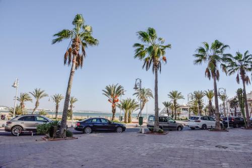 a parking lot with palm trees and parked cars at Marina Agadir Sunny Holiday in Agadir