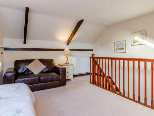 a living room with a leather chair and a staircase at The Tack Room - Uk30438 in Kingsbury Episcopi