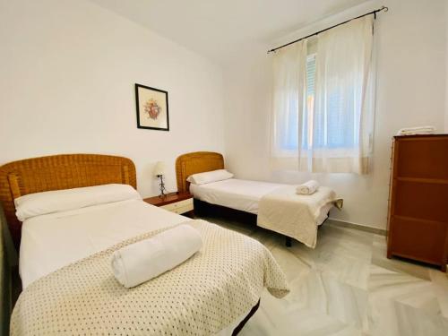 a room with two beds and a window at Villa palacio Playa y piscina Grupo AC Gestion in Cádiz