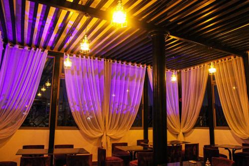 a room with purple curtains and tables and chairs at Majorel Pearl Hotel-Riad-Restaurant Piscine&Spa in Marrakech