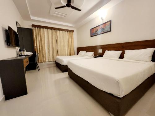 a hotel room with two beds and a ceiling fan at HOTEL PARK RAAMA in Tirupati