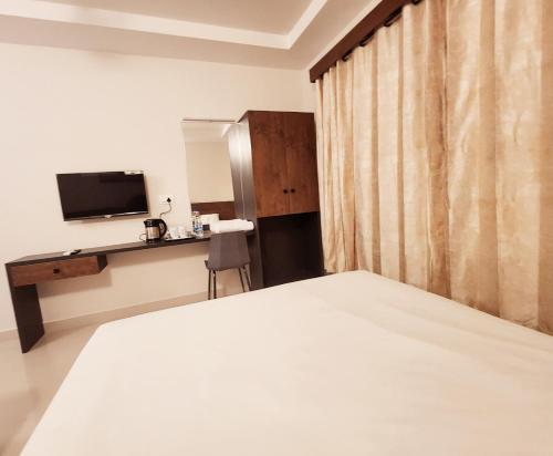 a bedroom with a bed and a desk and a television at HOTEL PARK RAAMA in Tirupati