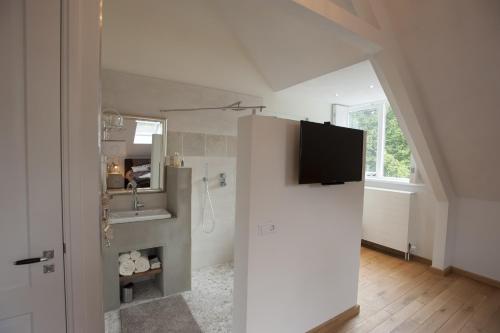 a bathroom with a sink and a tv on a wall at Boutique B&B Villa Heidetuin in Bergen op Zoom