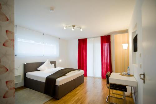 a hotel room with a bed and a table and a desk at Hotel Garni am Arbach in Eningen unter Achalm