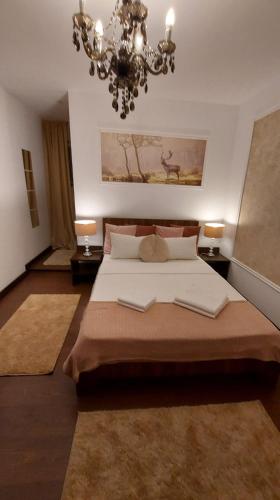 a bedroom with a large bed and a chandelier at Ambiennt in Bucharest