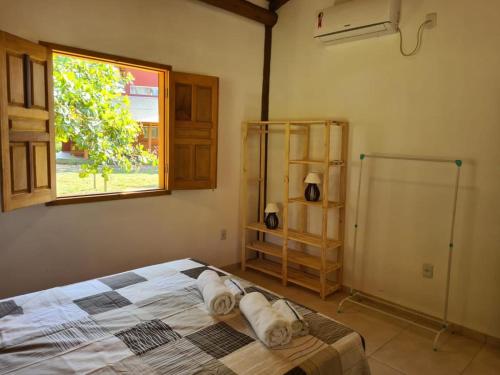 a bedroom with a bed with two pillows and a window at Chalé Amarelo, conforto e muita natureza - Mar Doce! in Caravellas